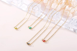 Detail of four colorful enamel evil eye necklaces in gold plating with ice decor