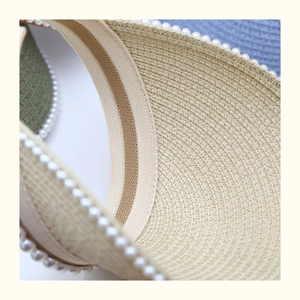 Close-up of straw sun hat brim with pearl beads and internal striped elastic band