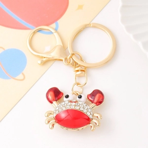 Detail of a gold crab keychain with red enamel and sparkling crystal rhinestones