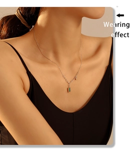 Detalle del collar minimalista chapado en oro de 18K con colgante de rayas verdes