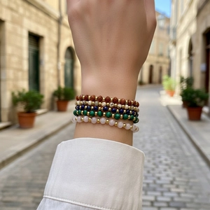 Detailed view of bohemian stacked bracelets with natural stones and gold metal beads on wrist