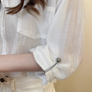 Detailed macro view of shirt cuff with decorative metal ball chain magnetic fastening buckle