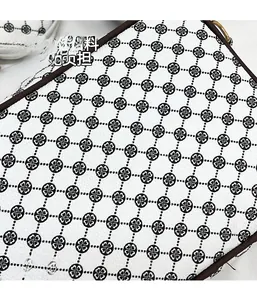 Close-up of white lychee leather texture with black clover pattern and brown trim edge
