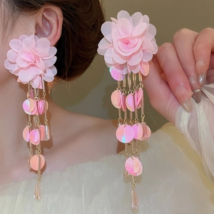 Detail of pink chiffon flower earrings with long sequin tassels on a female model