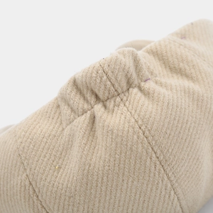Detailed macro view of light beige corduroy fabric texture with elastic stitching on cap