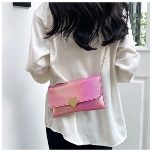 Detail of pink gradient envelope bag featuring a gold heart clasp and metal chain strap