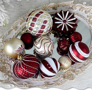 Detail of assorted red and gold Christmas ornaments on a vintage white mirrored tray