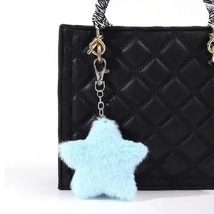 Close-up of fluffy light blue star-shaped plush pendant hanging on a black leather bag