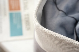 Close-up of white woven edge and grey quilted lining of the linen storage basket
