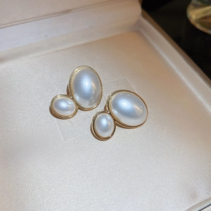 Detail of vintage gold-framed double pearl earrings on premium silk jewelry box lining