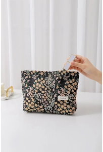 Detail of floral embroidery on black makeup bag showing lipstick storage capacity
