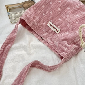 Dettaglio della borsa in velluto rosa con motivi a cuore bianchi ed etichetta tessuta