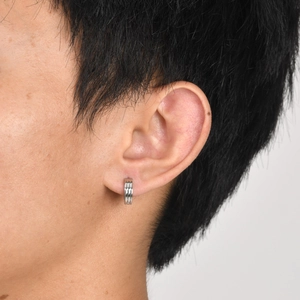 Close-up of a silver stainless steel triple-loop earring worn on a male model's ear