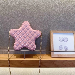 Detail of pink star-shaped quilted crossbody bag with golden chain on a shelf