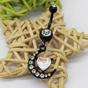 Macro detail of black moon belly ring with sparkling rhinestones and pink heart stone