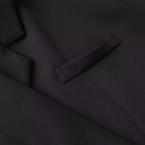 Detailed macro shot of premium black blazer fabric texture and refined stitching detail