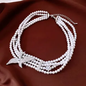 Three-layer vintage pearl necklace featuring eagle and star pendants on silk background