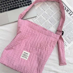 Detailed shot of pink pleated canvas bag with woven label on a lifestyle desk setup