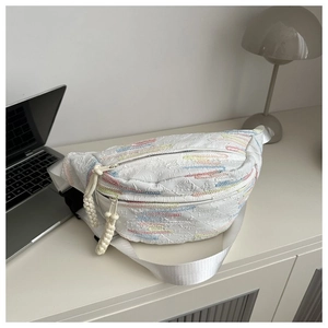 Close-up of white crossbody bag featuring colorful wavy jacquard texture and woven zipper pull