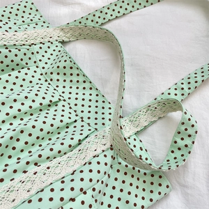Detailed close-up of mint green polka dot canvas tote with delicate white lace trim