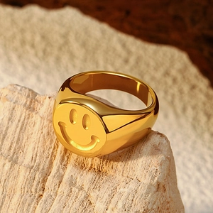 Close-up of a wide gold stainless steel signet ring with a minimalist smiley face engraving