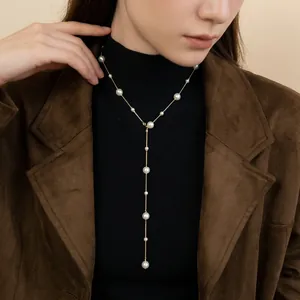 Elegant French style Y-shaped gold pearl necklace layered over a black turtleneck sweater