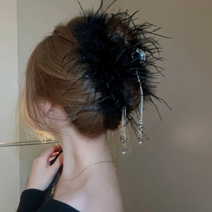 Detail of elegant black feather hair claw with sparkling long rhinestone tassels for women