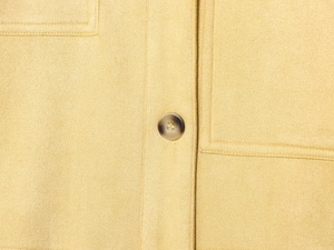 Close-up of mustard yellow faux suede jacket with dark brown textured button detailing