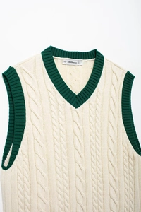 Detail of V-neck cable knit vest with green ribbed contrast edges and brand label
