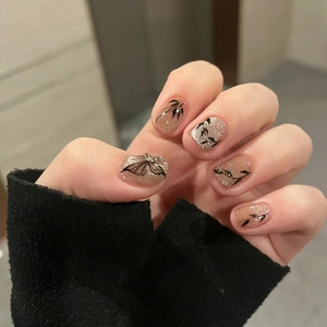 Unghie finte cat-eye con motivi di farfalle e foglie su base scintillante ed elegante