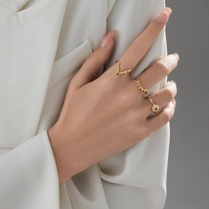Nahaufnahme eines dreiteiligen Goldring-Sets mit V-Form und Wellen-Design am Modell
