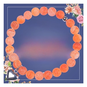 Close-up of 8mm orange agate beaded bracelet with silver heart charm on floral card