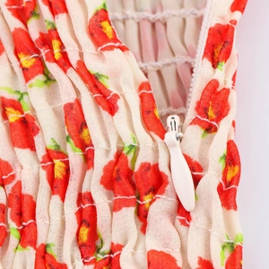 Detailopname van rode bloemenstof met witte rits en gerimpelde textuur van de kleding
