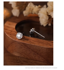 Macro detail of square zircon stud earrings in 925 silver on rustic wood background