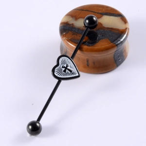 Detail of black stainless steel industrial barbell with a white heart and cross charm