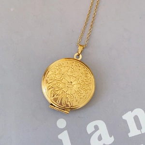 Gold round locket necklace featuring vintage floral embossed pattern and delicate chain