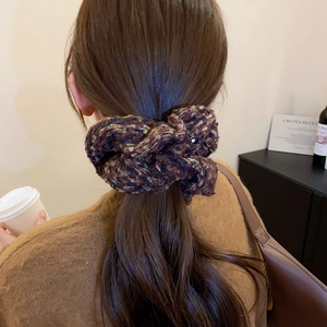 Détail d'un chouchou en tweed avec paillettes porté en queue de cheval à la maison
