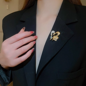 Detailed view of luxury gold heart brooch with sparkling rhinestones on black suit