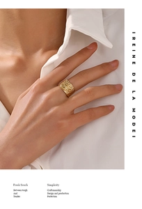 Gros plan d'une bague large dorée avec motif œil et texture striée sur le doigt