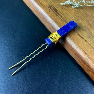 Detail of blue rectangular natural stone hand-wrapped with gold wire on a hair pin