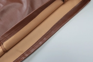 Detaillierte Nahaufnahme der braunen PU-Ledertextur und der präzisen Nähte am Kleid