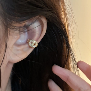 Macro detail of a gold-plated ear cuff with pavé crystals in a crisscross design