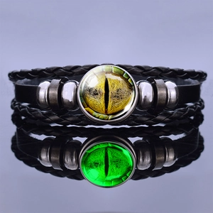 Detailed view of luminous dragon eye glass cabochon on black braided leather bracelet