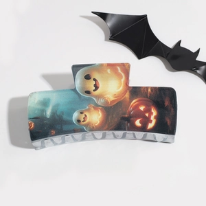 Detailed view of Halloween hair claw clip with ghost and pumpkin patterns on white surface