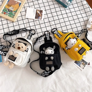 Detailed display of canvas crossbody bags with cartoon animal charms in three colors