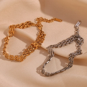 Detail of 18K gold and silver plated watch-strap style bracelets on silk background
