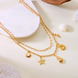 Double-layer gold necklace with shell starfish and conch charms on a minimalist stone base