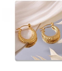 Detailed macro view of gold-plated PVD stainless steel C-shaped hoop earrings with hammered texture