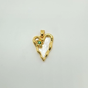 Detail of gold heart pendant with white mother of pearl and green stone flower inlay