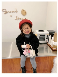 Girl's pearl crossbody bag worn with red beret in a stylish indoor cafe setting